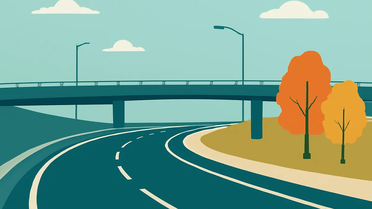 A highway with an overpass and two trees with orange and yellow leaves under a light blue sky with clouds