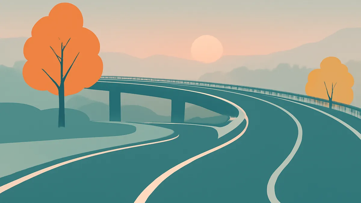 A highway interchange with an overpass and winding roads, with trees and mountains in the background at sunset