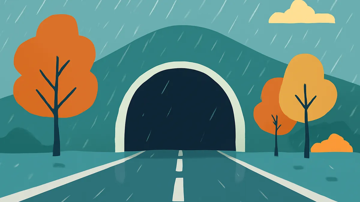 A road leading into a tunnel, with orange trees and rain falling