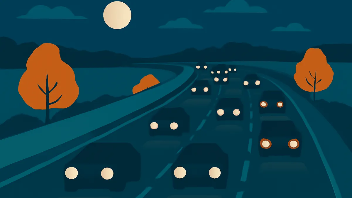 A highway at night with many cars driving, a full moon in the sky, and orange trees on the roadside