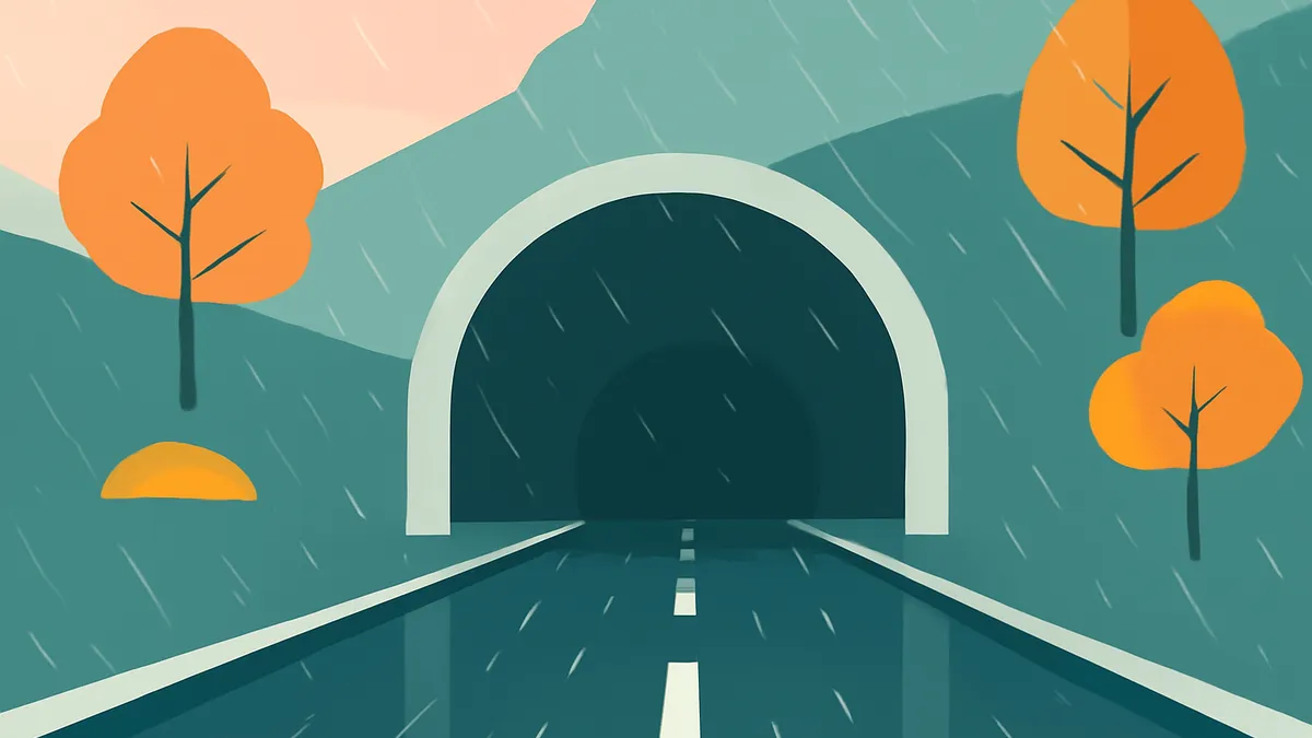 A road leading into a tunnel, surrounded by hills and trees, with rain falling