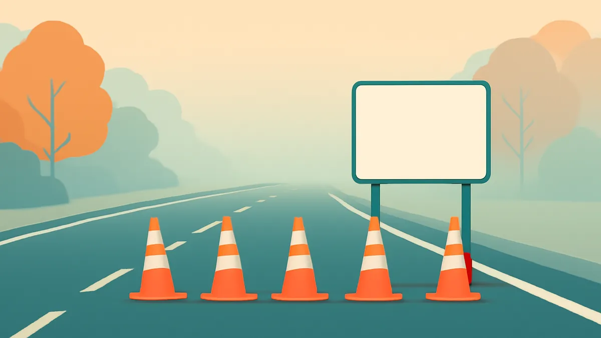 A highway with five orange traffic cones and a blank white sign on the right, with trees in the background