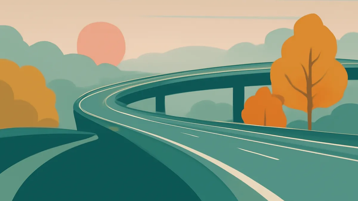 A winding highway overpass with a sunset in the background and trees in autumn colors