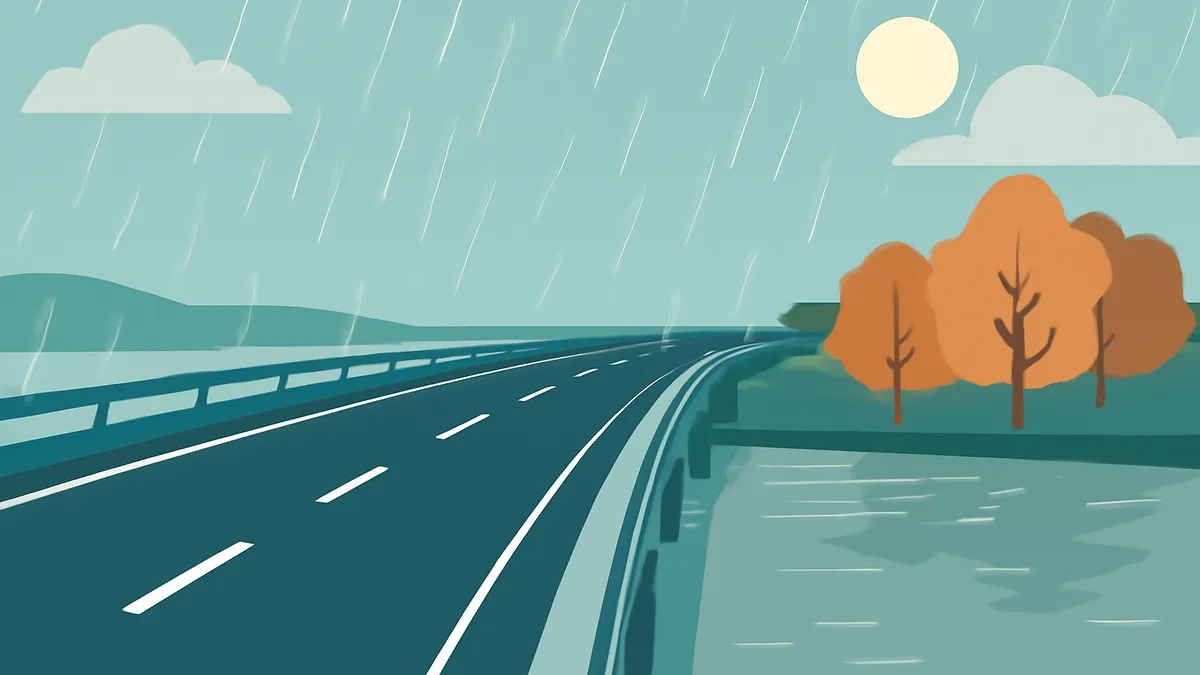 A highway curves to the right over a body of water, with trees on the right and hills in the distance, under a rainy sky